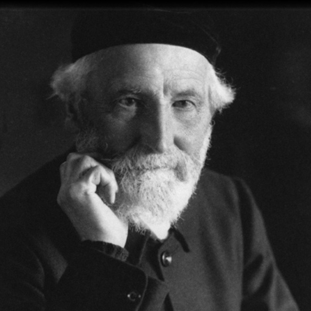 A black and white film portrait of Edwin Abbott Abbott. He is wearing a darker color suit jacket and a black beret. He has a white small beard with his right hand touch his chin. 