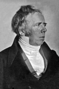 A profile black and white photograph of Hans Christian Orsted facing to the right. He is wearing a clergy outfit. He has some gray hairs within his dark hairs.