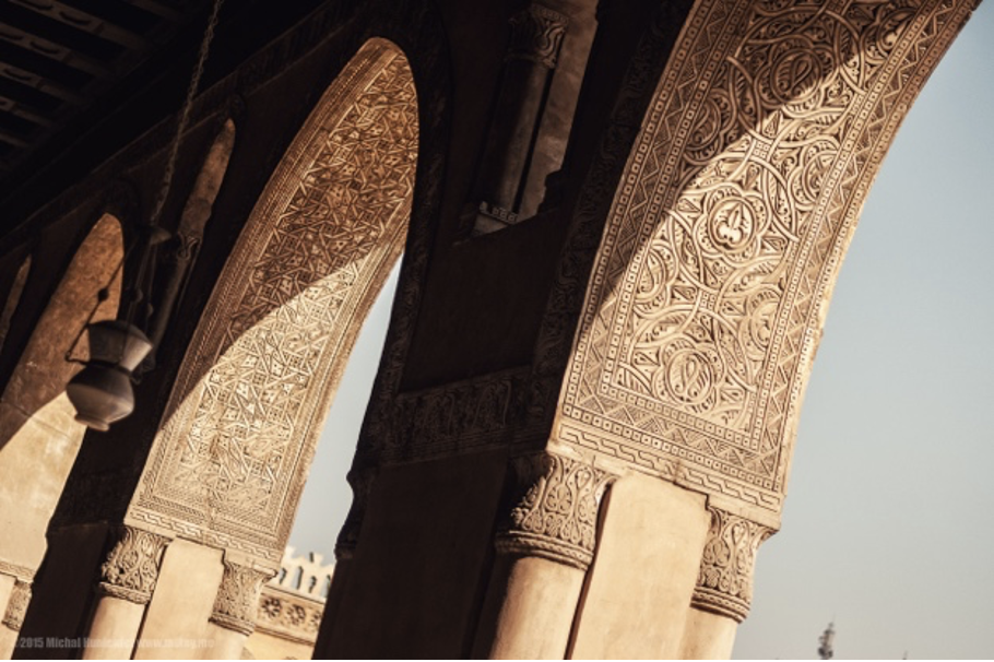 An image showing elaborately decorated brown stone arches within Ibn Tulun Mosque. 