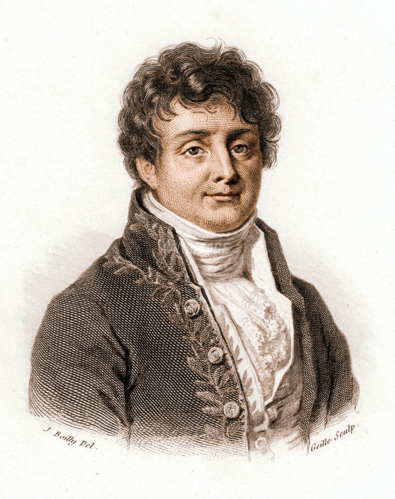 A painted portrait of Joseph Fourier. He is pictured from the waist up and is wearing a white shirt, white cravat, and a brown waistcoat. Additionally, he is smiling, clean-shaven and has brown curly hair. 