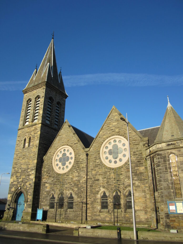 A color photograph of St Mark's Parish Church. The building is made out of  stone with a tower. 
